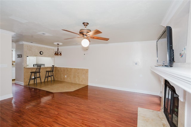 living room featuring a high end fireplace, wood-type flooring, ornamental molding, and ceiling fan