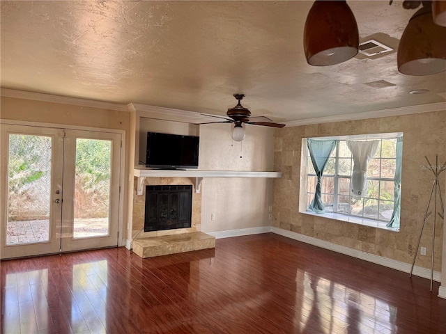 unfurnished living room with a tiled fireplace, crown molding, a textured ceiling, and hardwood / wood-style flooring