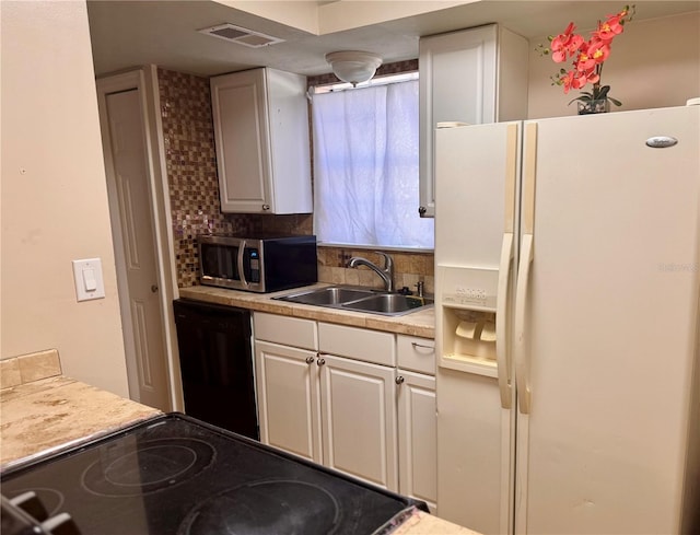 kitchen with sink, backsplash, white cabinets, and appliances with stainless steel finishes