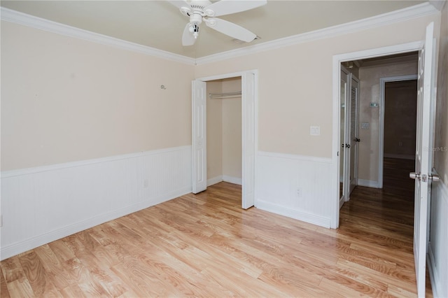 unfurnished bedroom featuring crown molding, light hardwood / wood-style flooring, a closet, and ceiling fan