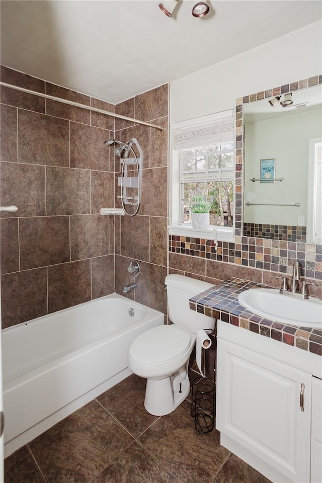 full bathroom featuring tile walls, backsplash, tiled shower / bath combo, vanity, and toilet