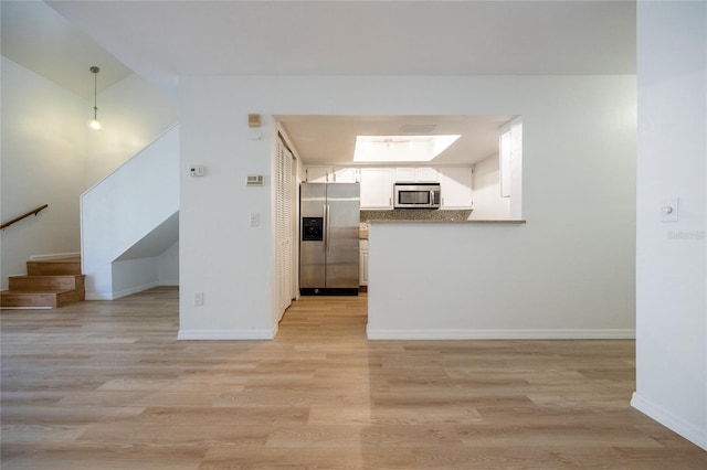 interior space featuring a skylight and light hardwood / wood-style floors