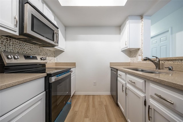 kitchen featuring sink, light hardwood / wood-style flooring, stainless steel appliances, tasteful backsplash, and white cabinets