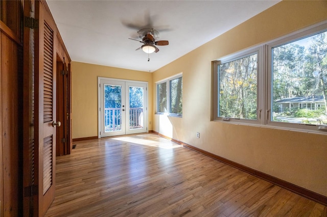 unfurnished room with ceiling fan, light wood-type flooring, and french doors