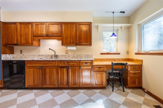 kitchen with sink, dishwasher, hanging light fixtures, light stone counters, and built in desk