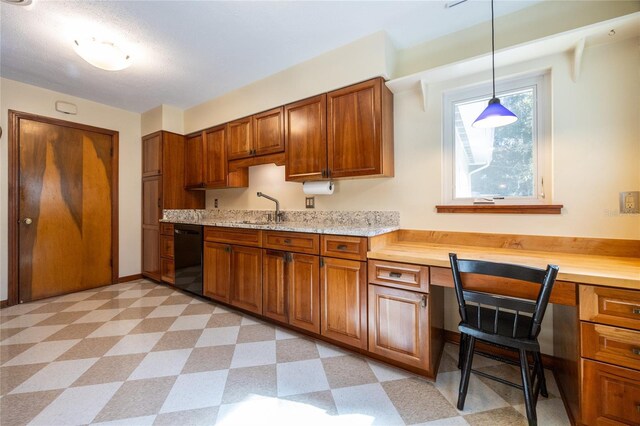 kitchen with sink, built in desk, black dishwasher, pendant lighting, and light stone countertops