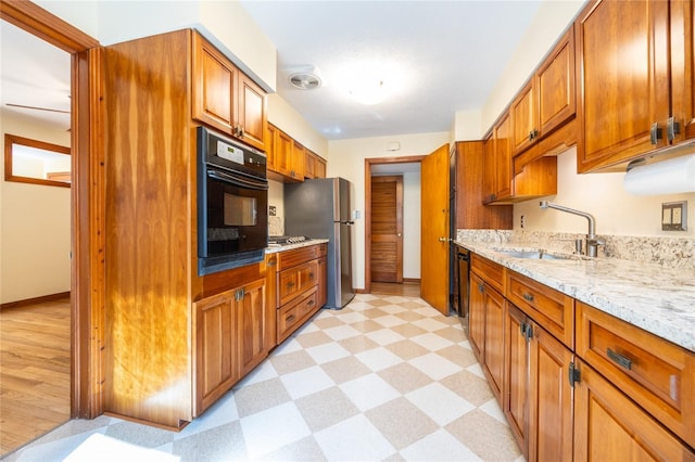 kitchen featuring sink, black appliances, and light stone countertops