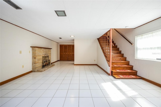 unfurnished living room featuring a stone fireplace and light tile patterned floors