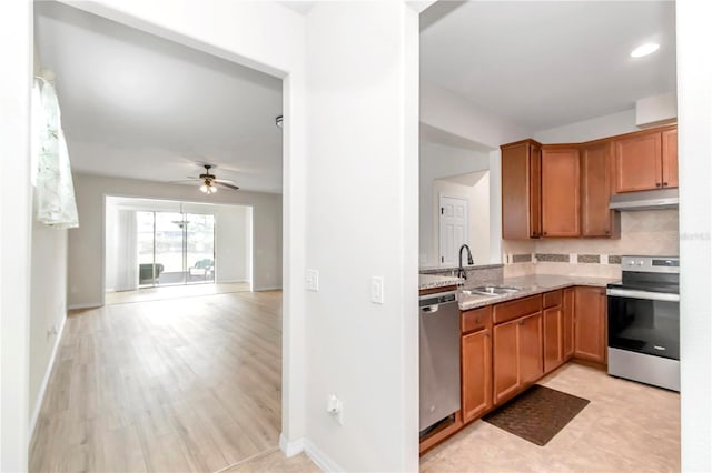 kitchen with sink, tasteful backsplash, appliances with stainless steel finishes, ceiling fan, and light stone countertops