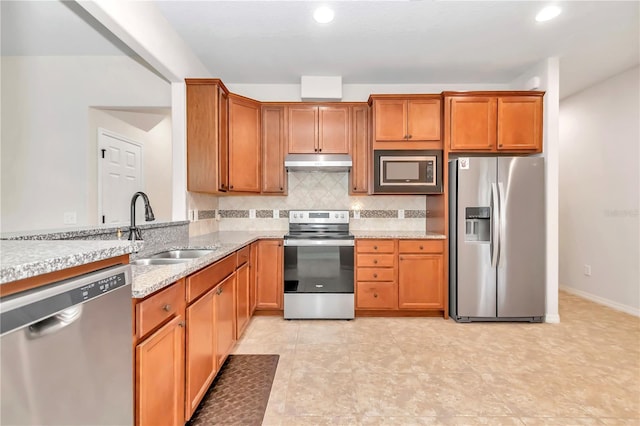 kitchen with tasteful backsplash, sink, light stone counters, and appliances with stainless steel finishes