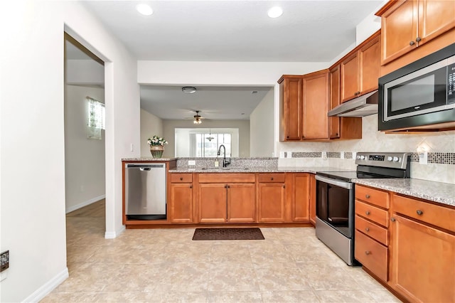 kitchen with sink, tasteful backsplash, ceiling fan, stainless steel appliances, and light stone countertops