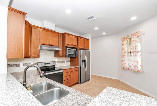 kitchen with stainless steel appliances, sink, light stone counters, and decorative backsplash