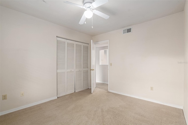 unfurnished bedroom with light colored carpet, a closet, and ceiling fan