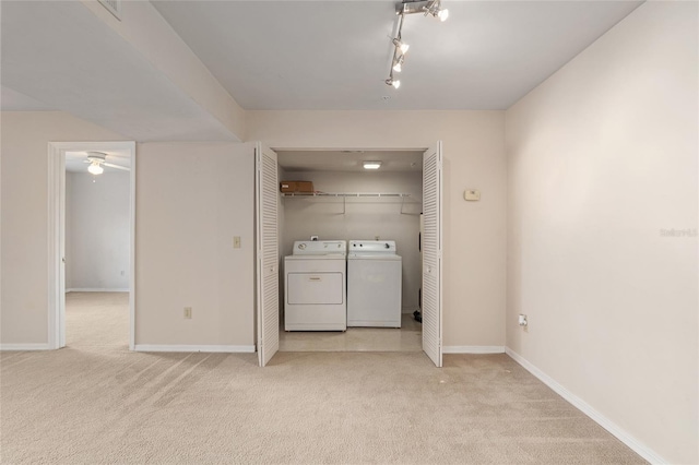 clothes washing area with separate washer and dryer, light colored carpet, and rail lighting