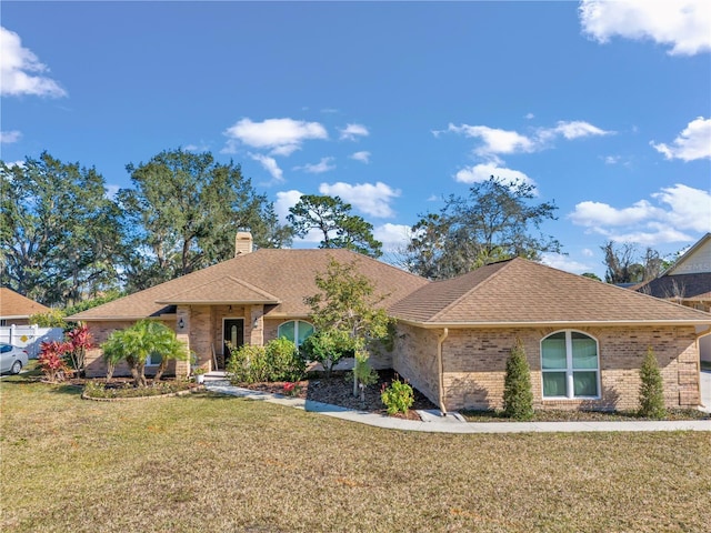 single story home with brick siding, a chimney, a front lawn, and roof with shingles