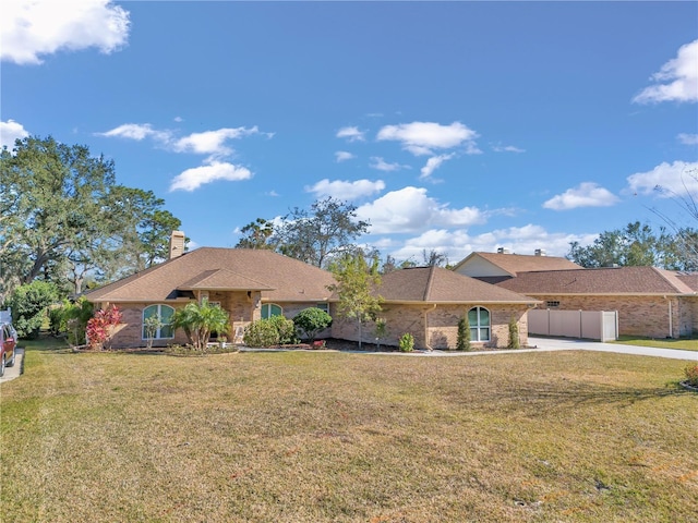 ranch-style home with a chimney, fence, a front lawn, and brick siding