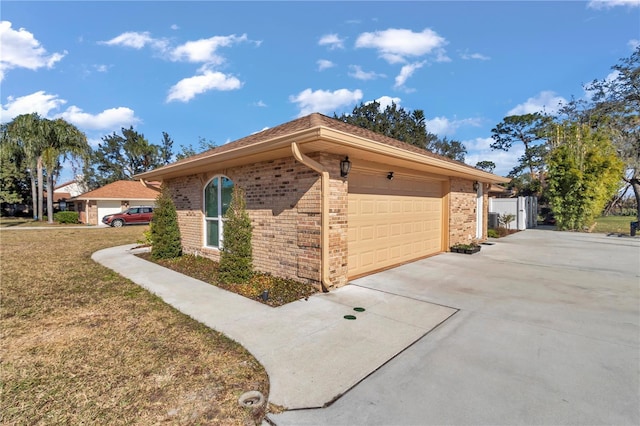 view of home's exterior featuring a garage, a yard, concrete driveway, and brick siding