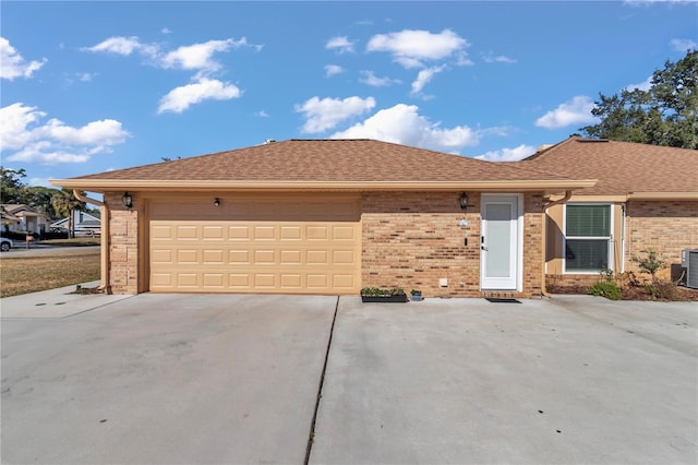 ranch-style home with a shingled roof, concrete driveway, brick siding, and an attached garage