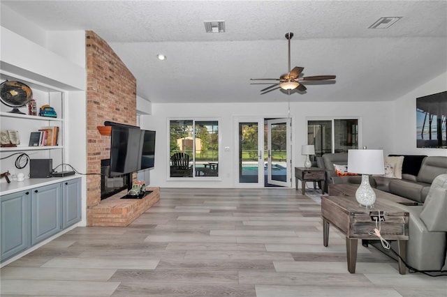 living area with visible vents, vaulted ceiling, a textured ceiling, and ceiling fan