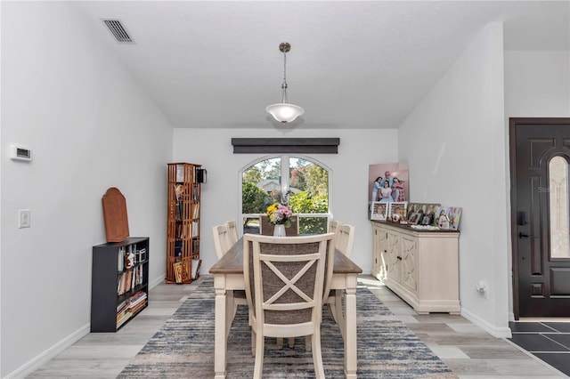 dining area with baseboards, visible vents, and light wood finished floors