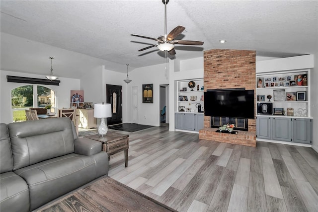 living area featuring a textured ceiling, lofted ceiling, wood finished floors, a ceiling fan, and built in features