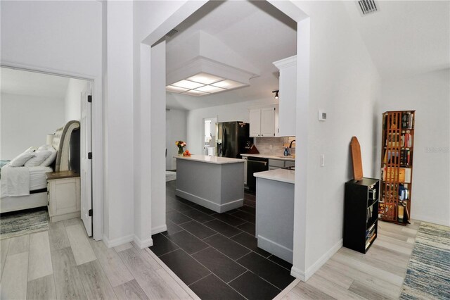 kitchen with light countertops, decorative backsplash, white cabinets, a kitchen island, and black appliances