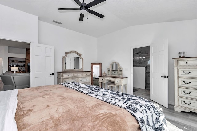 bedroom featuring a ceiling fan, light wood-type flooring, visible vents, and vaulted ceiling