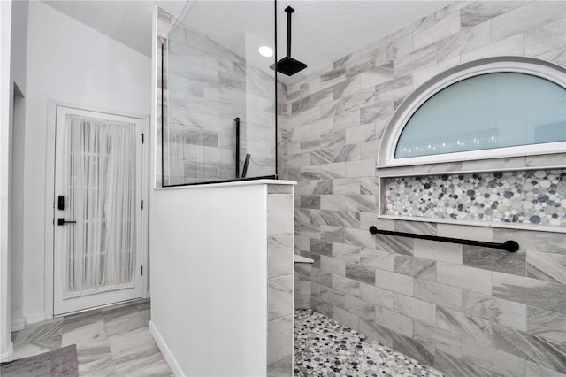 bathroom with marble finish floor, a textured ceiling, baseboards, and walk in shower