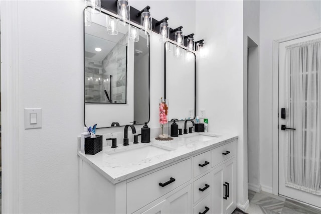 bathroom with a tile shower, double vanity, and a sink