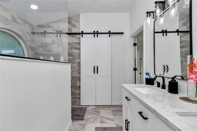 full bath featuring marble finish floor, double vanity, lofted ceiling, a sink, and a walk in shower