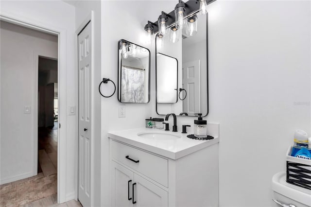 bathroom with toilet, a closet, and vanity