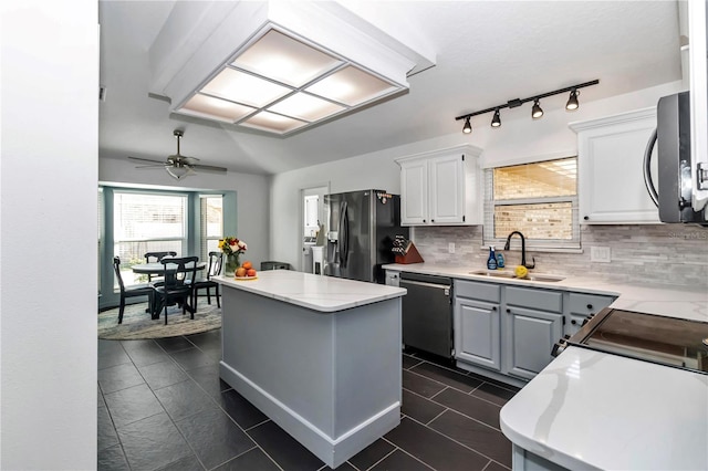 kitchen with black refrigerator with ice dispenser, light countertops, stainless steel dishwasher, white cabinetry, and a sink