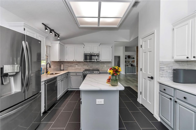 kitchen with light stone counters, a center island, stainless steel appliances, white cabinets, and a sink