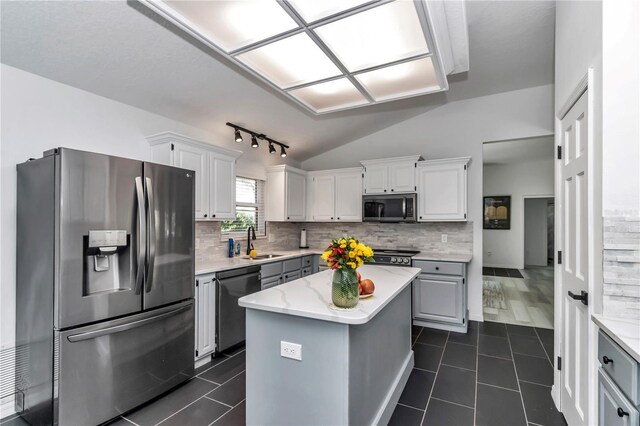 kitchen featuring stainless steel appliances, white cabinets, a kitchen island, and a sink