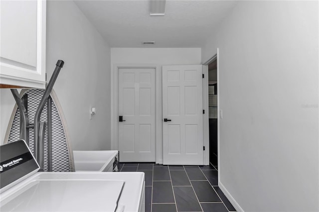 clothes washing area featuring dark tile patterned flooring, visible vents, baseboards, cabinet space, and washer and clothes dryer