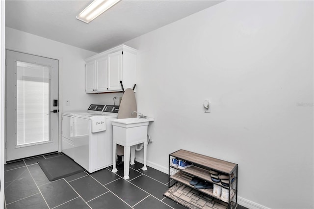 laundry area featuring cabinet space, dark tile patterned floors, baseboards, and separate washer and dryer