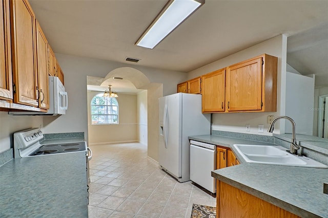 kitchen with sink, white appliances, light tile patterned floors, and a chandelier