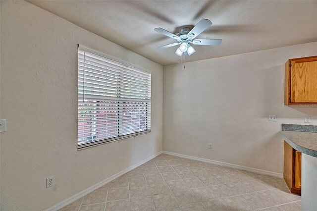 unfurnished dining area with ceiling fan and light tile patterned flooring