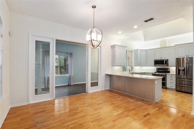 kitchen featuring sink, tasteful backsplash, decorative light fixtures, kitchen peninsula, and stainless steel appliances