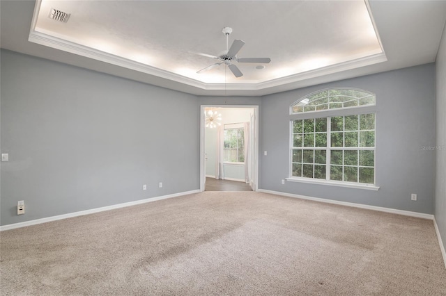 empty room with ceiling fan, a raised ceiling, and carpet