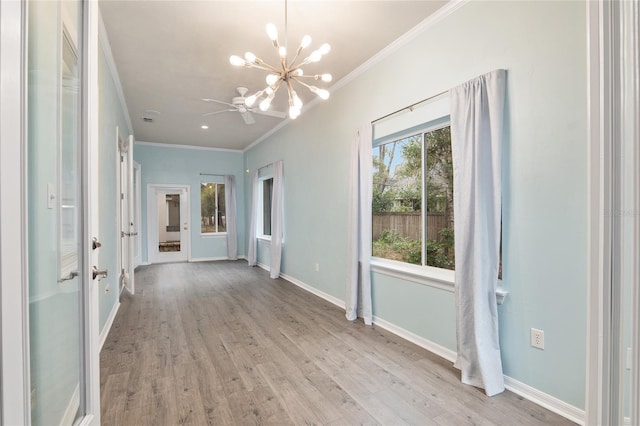 spare room with ornamental molding, an inviting chandelier, and light hardwood / wood-style flooring