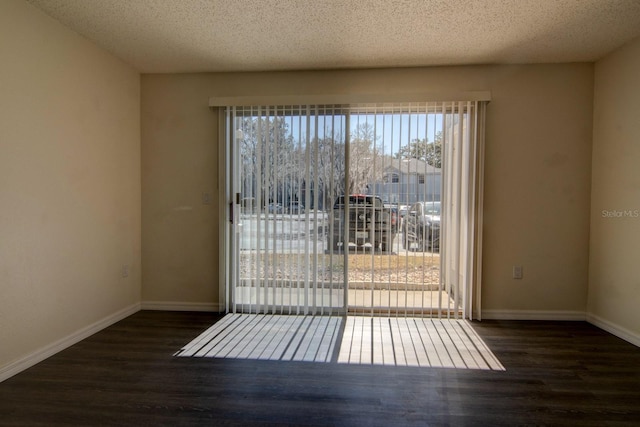 spare room featuring dark hardwood / wood-style floors and a textured ceiling