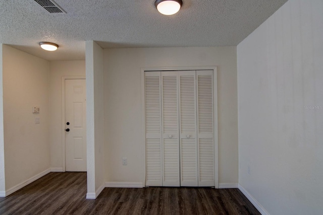 unfurnished bedroom featuring dark hardwood / wood-style floors, a closet, and a textured ceiling