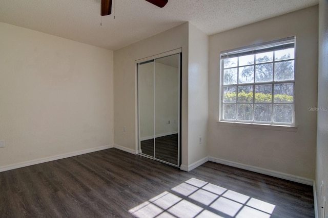 unfurnished bedroom with ceiling fan, dark hardwood / wood-style floors, a closet, and a textured ceiling