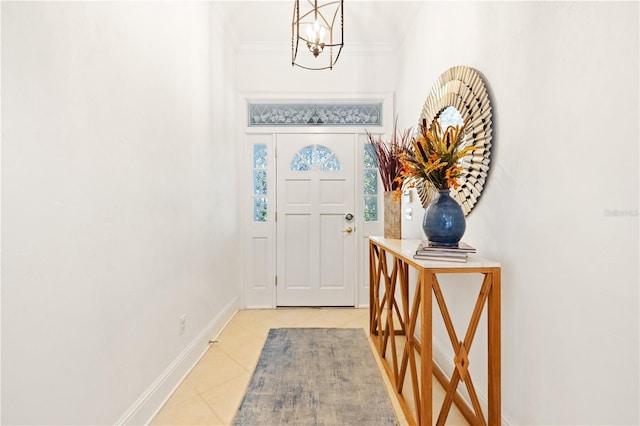 foyer entrance featuring an inviting chandelier, light tile patterned floors, and ornamental molding