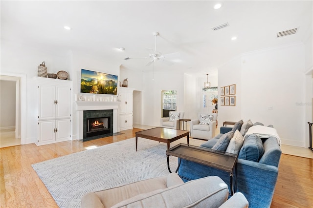 living room featuring ornamental molding, ceiling fan, and light wood-type flooring