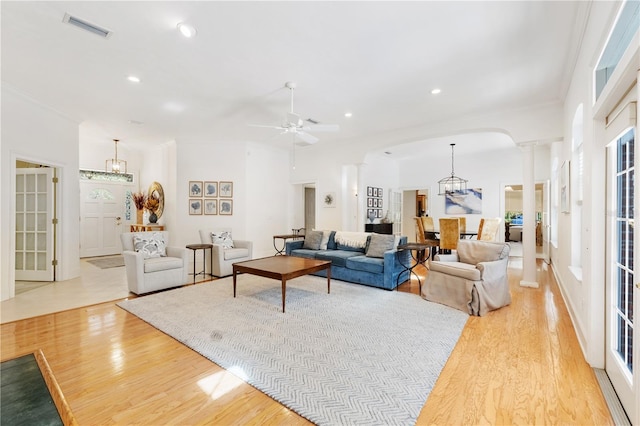 living room featuring ceiling fan with notable chandelier, lofted ceiling, light hardwood / wood-style floors, and ornate columns