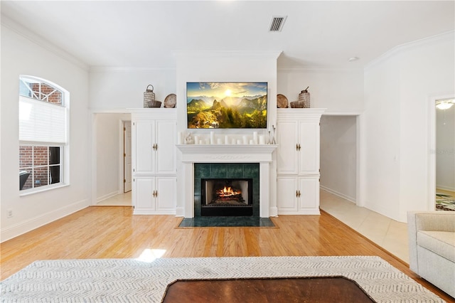 unfurnished living room featuring hardwood / wood-style floors, ornamental molding, and a tile fireplace