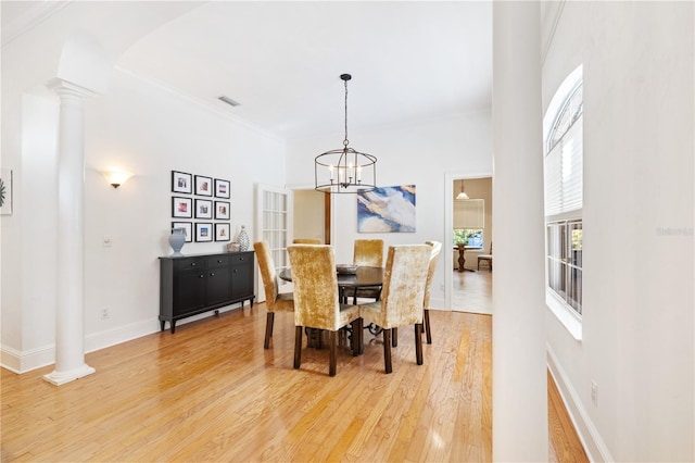 dining room featuring hardwood / wood-style flooring, ornamental molding, an inviting chandelier, and ornate columns