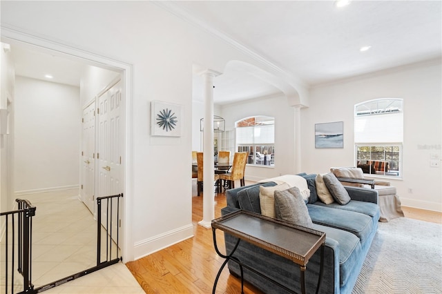 living room featuring ornamental molding, light hardwood / wood-style floors, and ornate columns